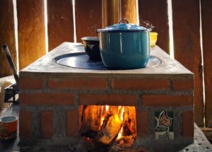 Front view of ECOLIFE's Patsari stove is use with a blue and black pot set on top. The fire powering the stove is visible through a small opening.